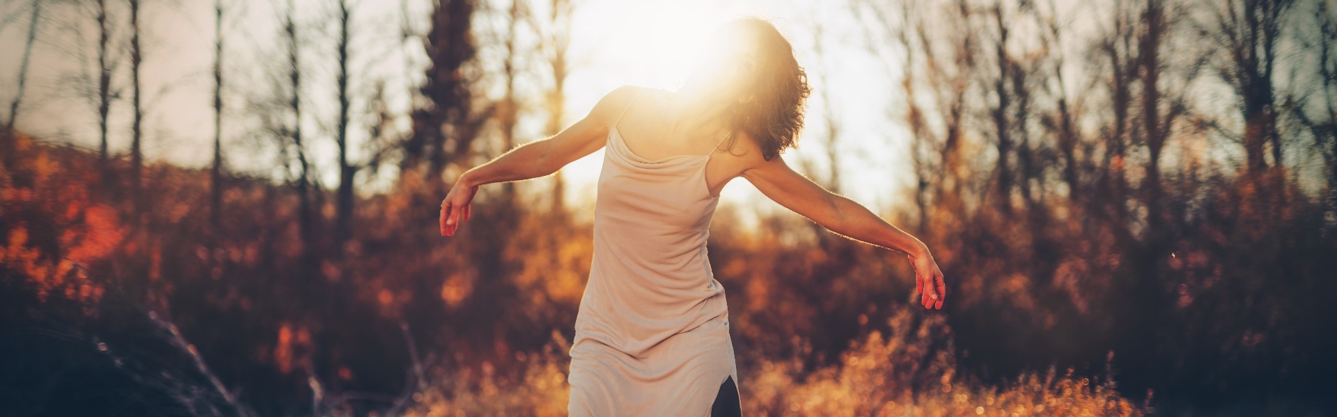 Beautiful woman dancing in nature at sunset.